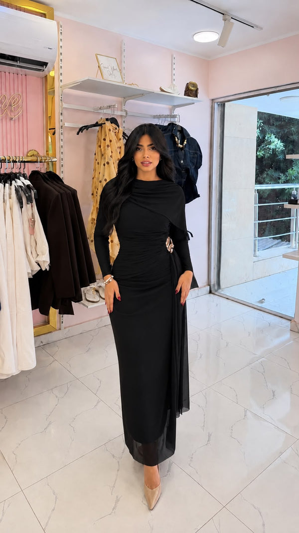 An evening dress made of tulle, featuring ruched details and a draped cape.