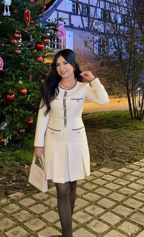 A short, elegant pleated tweed dress embellished with pearls and timeless black accents.