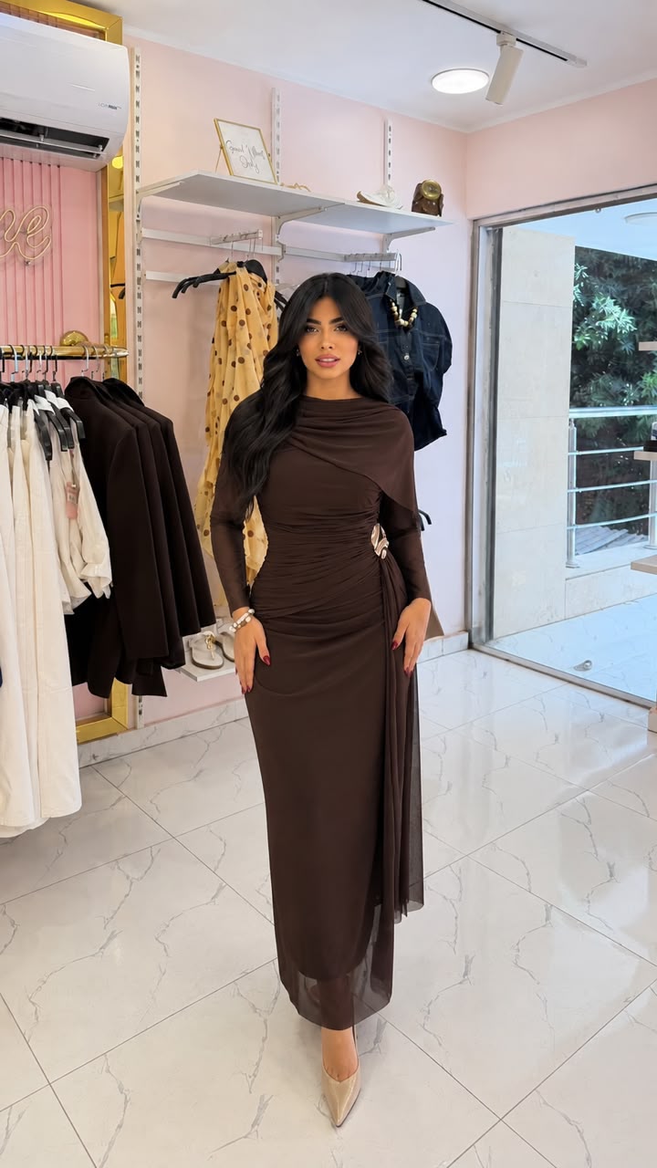 An evening dress made of tulle, featuring ruched details and a draped cape.